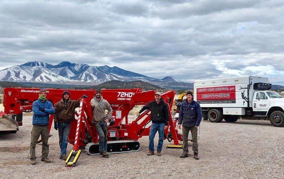 Mick's Tree Service crew beside a red aerial lift and company truck in Flagstaff.
